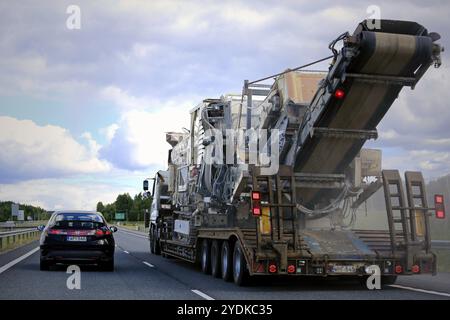 Der Auflieger transportiert große Metso-Brecher im Autobahnverkehr, Rückansicht vom überholenden Auto, Staubspur von der Straße. Salo, Finnland, 30. Juni 2018, Stockfoto