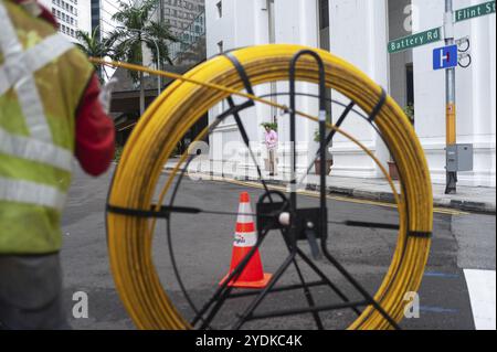 15.04.2018, Singapur, Republik Singapur, Asien, Ein Arbeiter verlegt Kabel auf einer Straße im Geschäftsviertel in Asien Stockfoto