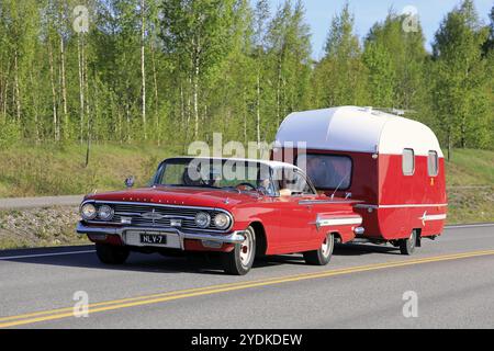 Salo, Finnland. Mai 2019. Klassisches rotes Chevrolet Impala Cabrio aus den 1960er Jahren mit passendem Vintage-Caravan auf der Autobahn des Salon Maisema Cruising 2019 Stockfoto