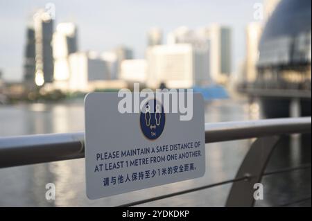 02.12.2020, Singapur, Republik Singapur, Asien, Ein Schild auf einem Geländer an der Uferpromenade in Marina Bay weist auf die Regeln für die sichere Distanz und die Rémin hin Stockfoto