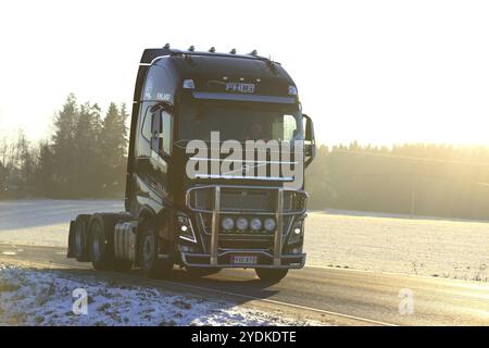 SALO, FINNLAND, 6. JANUAR 2017: Der schwarze Volvo FH-Sattelzugmaschine von MHL Trans bewegt sich im goldenen Licht des Sonnenuntergangs auf der Winterautobahn Stockfoto