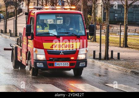 Roter Mitsubishi-Abschleppwagen von Viking Assistance Oy fährt morgens auf der Straße, Lichter blinken. Helsinki, Finnland. April 2021 Stockfoto