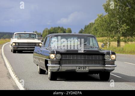 SOMERO, FINNLAND, 5. AUGUST 2017: Der klassische schwarze Cadillac fährt mit anderen Oldtimern auf der Maisemaruise 2017 in Tawastia entlang der landschaftlich reizvollen Autobahn Stockfoto