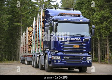 LAUKAA, FINNLAND, 22. SEPTEMBER 2017: Dunkelblauer Scania R730 Holzfällerwagen mit einer Holzladung, die mit Fichtenwald auf dem Hintergrund auf Scania La geparkt ist Stockfoto