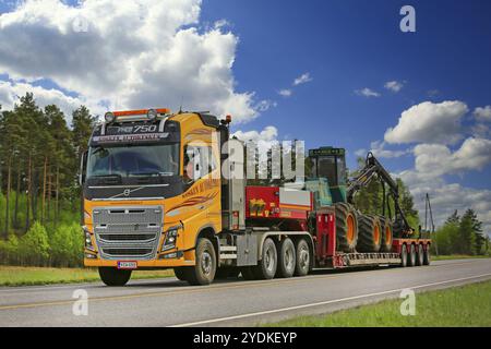 SALO, FINNLAND, 25. MAI 2017: Der gelbe Volvo FH von Kosken Autokeskus transportiert den Logman 811H Waldernter auf einem Schwanenhalsanhänger auf der Autobahn auf einem Beau Stockfoto