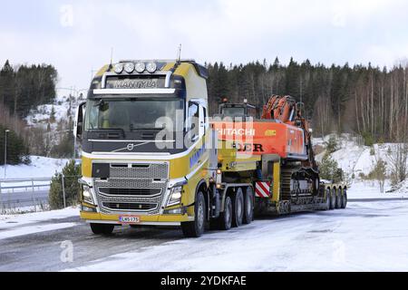 Salo, Finnland, 9. März 2019: Volvo FH16 Truck Mantyla mit Tieflader-Anhänger mit Hitachi ZX 350LC-Bagger als breite Last an einem Wintertag, EU Stockfoto