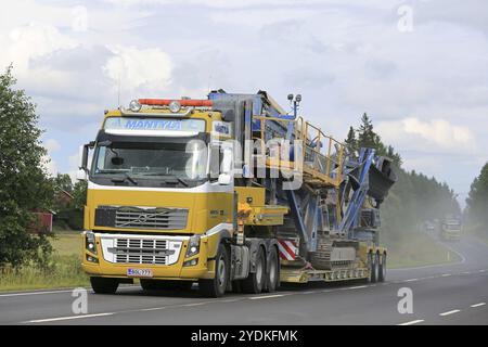 SALO, FINNLAND, 30. JULI 2016: Der gelbe Volvo FH von EE Mantyla transportiert Fintec 570 Screen auf einem Lowboy-Anhänger entlang der Autobahn. Eine weitere schwere Transportfoll Stockfoto