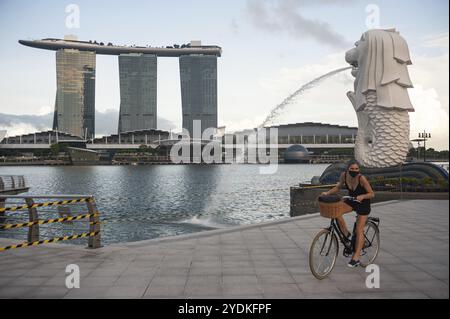 28.05.2020, Singapur, Republik Singapur, Asien, Eine Frau fährt mit dem Fahrrad entlang des ansonsten verlassenen Merlion Park am Ufer des Singapur Stockfoto