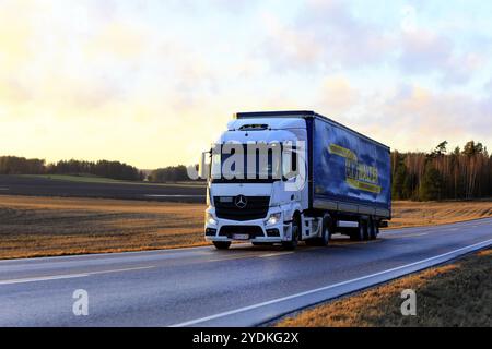 Der weiße Mercedes-Benz Actros-Lkw zieht LKW Walter Güterwagen auf der Autobahn 52 bei Sonnenuntergang im Frühjahr. Salo, Finnland. Februar 2020 Stockfoto