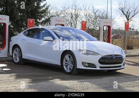 PAIMIO, FINNLAND, 18. MÄRZ 2017: Das weiße Tesla Model S P85D Elektroauto wird am Tesla Supercharger aufgeladen. Die Kompressorstationen fügen CA 1 hinzu Stockfoto