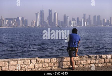 13.09.2010, Doha, Katar Qatar, Ein Mann, der an der Promenade entlang der Al Corniche Street angelt und einen Blick auf die Skyline des Al Dafna Geschäftsviertels in bietet Stockfoto