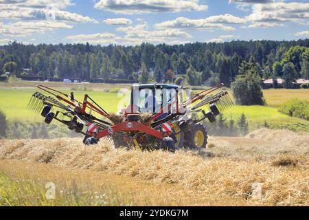 Landwirt, der auf dem Feld mit John Deere 6420S Traktor und Fella Drehrechen arbeitet und trockenes Stroh am Spätsommer schwärzt. Salo, Finnland. August 2020 Stockfoto