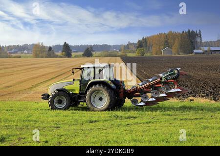 Bauer Pflügefeld mit grünen Valtra Traktor und Pflügen an einem sonnigen Herbstnachmittag in Südfinnland. Jokioinen, Finnland. Oktober 2020 Stockfoto