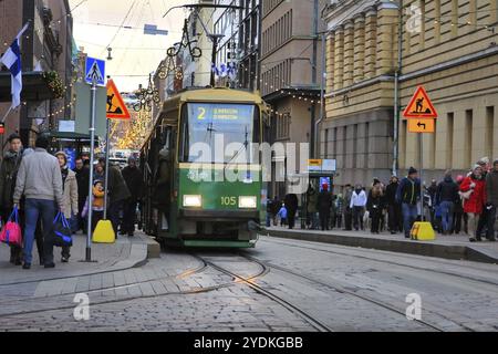 Shopper und Reisende im überfüllten Aleksanterinkatu mit der grünen HSL-Straßenbahn an der Senaatintori-Straßenbahnhaltestelle. Helsinki, Finnland. Dezember 2017 Stockfoto