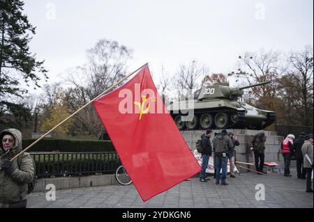 25.11.2023, Berlin, Deutschland, Europa, im Vorfeld einer Friedensdemonstration steht ein Demonstrant mit roter sowjetischer Flagge an der sowjetischen Gedenkstätte in Th Stockfoto