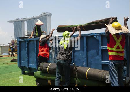 04.04.2018, Singapur, Republik Singapur, Asien, Arbeiter verfügen über Kunstrasen in der Marina Bay, während das Marina Bay Sands Hotel zu sehen ist Stockfoto