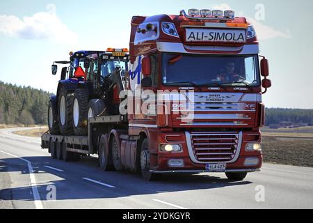 SALO, FINNLAND, 21. APRIL 2017: Der DAF XF Sattelzugwagen von Ali-Simola transportiert im Frühjahr zwei landwirtschaftliche Traktoren auf einem Schwanenhals-Anhänger entlang der Straße Stockfoto