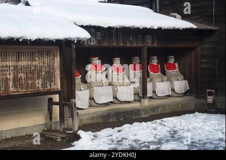 29.12.2017, Takayama, Gifu, Japan, Asien, eine Reihe von Jizo-Statuen aus Stein, bedeckt mit roten Kappen und Lätzchen, befindet sich unter einem hölzernen Vordach auf dem Gelände von HID Stockfoto