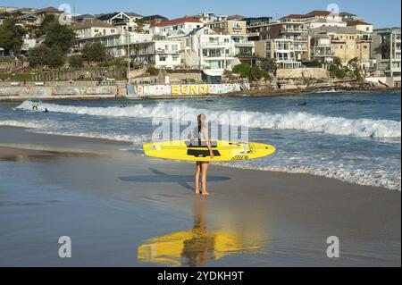 21.09.2018, Sydney, New South Wales, Australien, Eine junge Surferin steht am Bondi Beach mit ihrem Surfbrett unter dem Arm und blickt auf das Meer, Ozeanien Stockfoto