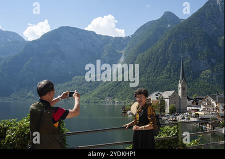 18. Juni 2019, Hallstatt, Oberösterreich, Österreich, Europa, chinesische Touristen machen Fotos über dem Hallstättersee mit der Kirche und den Bergen im Hintergras Stockfoto