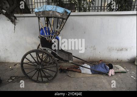 25.02.2011, Kalkutta, Westbengalen, Indien, Asien, ein Rikscha-Fahrer schläft neben seiner hölzernen Rikscha an einem Straßenrand in Kalkutta, der einzigen Stadt Indiens Stockfoto