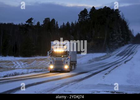 SALO, FINNLAND, 7. JANUAR 2017: Ein maßgeschneiderter Super Scania-Sattelzug von T. Salminen Transport mit glänzenden Scheinwerfern transportiert Güter in der Abenddämmerung auf Schnee Stockfoto