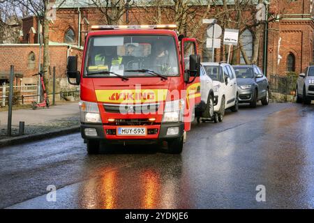 Roter Mitsubishi Abschleppwagen von Viking Assistance Oy bei der Arbeit in der Stadt, Lichter reflektieren auf der Straße. Helsinki, Finnland. April 2021 Stockfoto