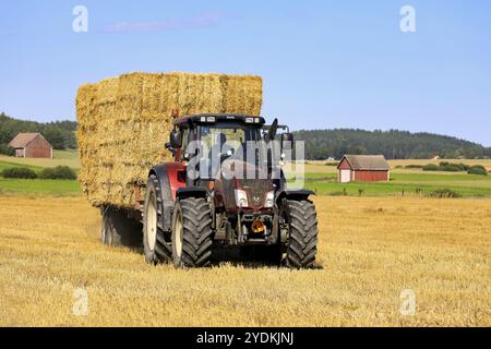 Transport von Strohballen mit Valtra-Traktor und landwirtschaftlichem Anhänger vom Erntefeld zur Lagerung im Spätsommer. Salo, Finnland. August 2020 Stockfoto