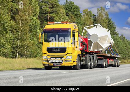 Der gelbe MAN Kranwagen K. Jousmaa transportiert an einem sonnigen Nachmittag Industriegegenstände auf einem Anhänger. Road 25, Raasepori, Finnland. September 2021 Stockfoto