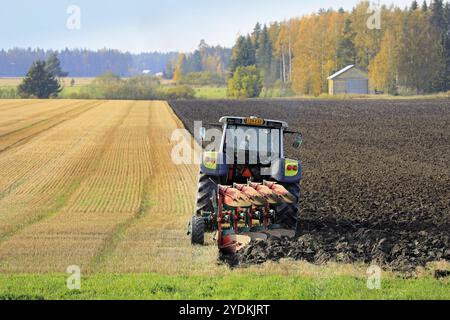 Bauer Pflügefeld mit grünen Valtra Traktor und Pflügen an einem sonnigen Herbstnachmittag in Südfinnland. Jokioinen, Finnland. Oktober 2020 Stockfoto