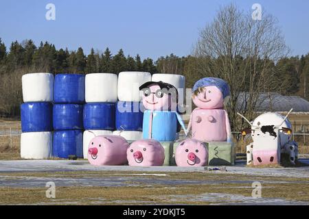 LIETO, FINNLAND, 5. MÄRZ 2017: Stillleben auf einem Feld aus Silageballen von unbekannt mit der Flagge Finnlands, dem Bauernpaar und Nutztieren Stockfoto