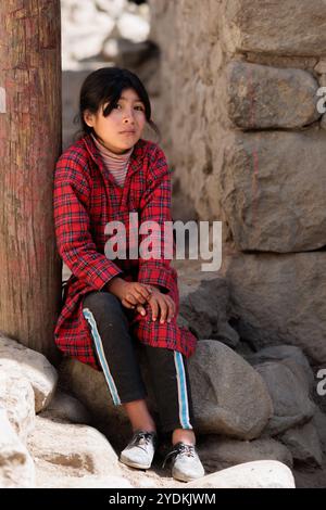 Peru - Tupe, 23. Oktober 2022: Eine junge Frau in traditioneller Kleidung entspannt sich im Schatten entlang der Straßen von Tupe in den Bergen Perus Stockfoto