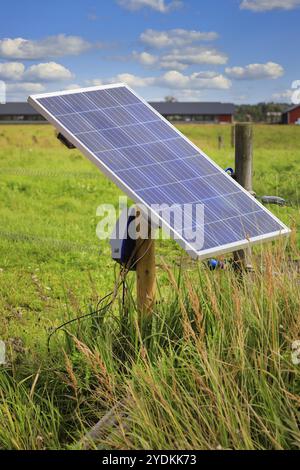 Ladegerät für elektrische Zäune für Solarmodule auf einem Holzmast, das die Energie für elektrische Viehzäune auf ländlichen Ackerflächen in Finnland liefert Stockfoto