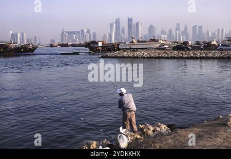 13.09.2010, Doha, Katar Qatar, Ein Mann, der an der Promenade entlang der Al Corniche Street angelt und einen Blick auf die Skyline des Al Dafna Geschäftsviertels in bietet Stockfoto