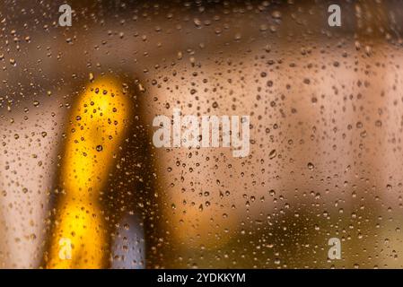 Nahaufnahme von Regentropfen in einem Glas in Schwarz-weiß mit Hintergrund von diffusen Lichtern Stockfoto