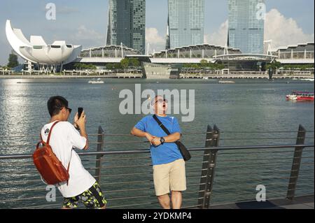 19.07.2019, Singapur, Republik Singapur, Asien, Touristen posieren für Fotos am Ufer des Singapore River mit dem Marina Bay Sands Hotel in Th Stockfoto