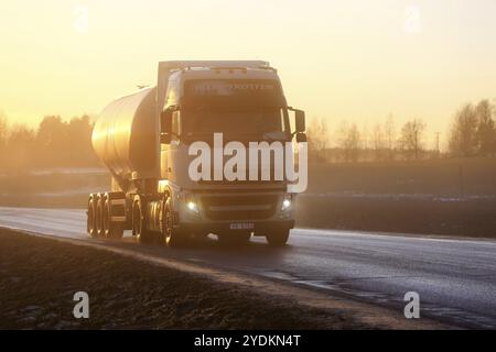 Der weiße Volvo FH Sattelschlepper fährt bei Sonnenuntergang im Winter durch dicken, sonnendurchfluteten Nebel auf der Straße. Salo, Finnland. Januar 2017 Stockfoto