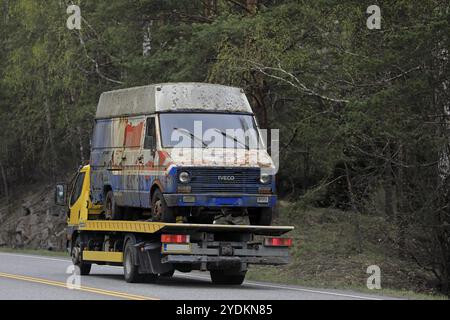 Salo, Finnland, 26. April 2019: Gelber Mitsubishi Fuso Canter-Abschleppwagen fährt an einem Frühlingstag einen alten Van entlang der Autobahn, Rückansicht, Europa Stockfoto