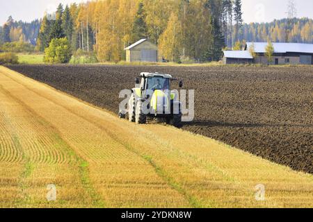 Bauer Pflügefeld mit grünen Valtra Traktor und Pflügen an einem sonnigen Herbstnachmittag in Südfinnland. Jokioinen, Finnland. Oktober 2020 Stockfoto