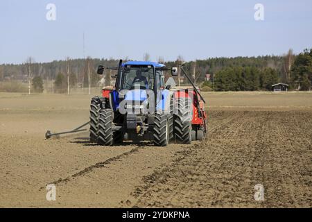 SALO, FINNLAND, 14. MAI 2017: Landwirt bebaut Feld mit blauem New Holland Traktor und Bohrmaschine an einem klaren Frühlingstag in Südfinnland Stockfoto