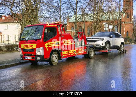 Roter Mitsubishi-Abschleppwagen von Viking Assistance Oy, der ein Auto in der Stadt abschleppt. Helsinki, Finnland. April 2021 Stockfoto