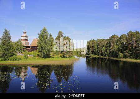 Finnischer blauer See und Himmelslandschaft mit UNESCO-Weltkulturerbe, alte Holzkirche Petajavesi, Finnland im Sommer. Die Kirche wurde 1763-65 erbaut Stockfoto