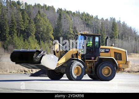 PAIMIO, FINNLAND, 18. MÄRZ 2017: Radlader und Kehrmaschine CAT 938K bei der Arbeit zur Reinigung eines Asphaltplatzes im Frühjahr Stockfoto