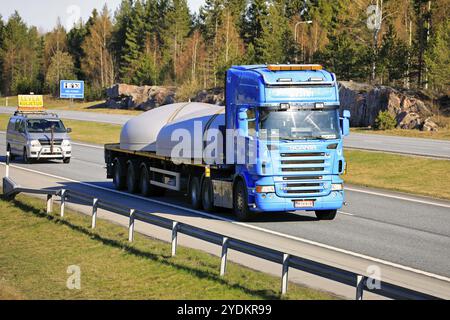 Blauer Scania-Auflieger, der kreisförmige Stahlgegenstände als Übergröße transportiert, unterstützt durch Begleitfahrzeug. Salo, Finnland. 30. April 2021 Stockfoto