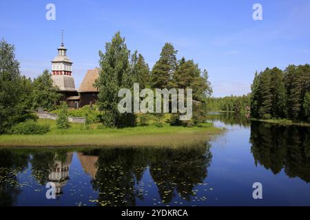 Finnischer blauer See und Himmelslandschaft mit UNESCO-Weltkulturerbe, alte Holzkirche Petajavesi, Finnland im Sommer. Die Kirche wurde 1763-65 erbaut Stockfoto