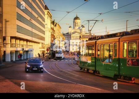 Zwei Straßenbahnen und langsamer Verkehr in Etelaeranta, Helsinki, Finnland an einem frühen Wintermorgen. Die Kathedrale von Helsinki im Hintergrund. Personen und Fahrzeuge pur Stockfoto