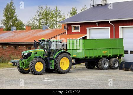 John Deere 6155R Traktor vor dem Palmse 1900 Anhänger auf dem Hof an einem Tag des frühen Herbstes. Salo, Finnland. August 2020 Stockfoto