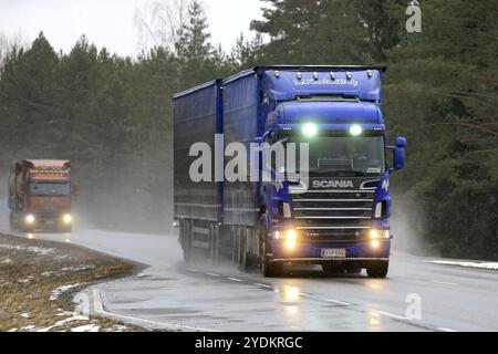 SALO, FINNLAND, 4. MÄRZ 2017: Blaues Scania R620 Kombifahrzeug von M. Keskimaki und einem anderen Lkw transportieren Güter auf nassen Straßen bei Schneefall Stockfoto