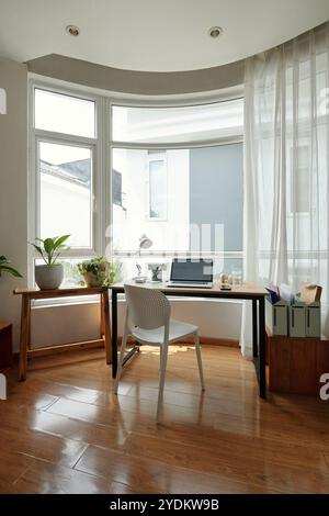 Sonnendurchfluteter Arbeitsbereich mit Blick auf den Garten und Holzfußboden Stockfoto