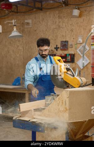 Geschulter Zimmermann, der Holzbohle mit Rundkreissäge an der Werkbank sägt Stockfoto